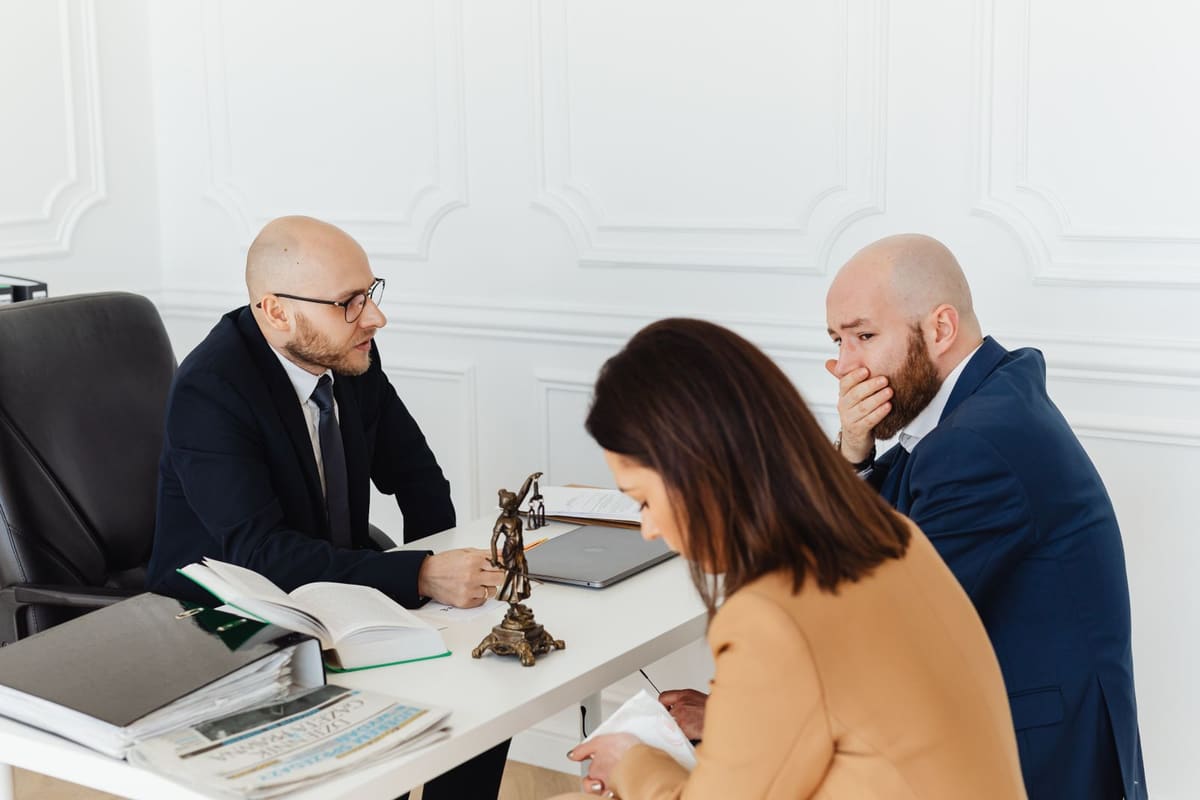 Two people meeting with an advisor across a desk in a formal office