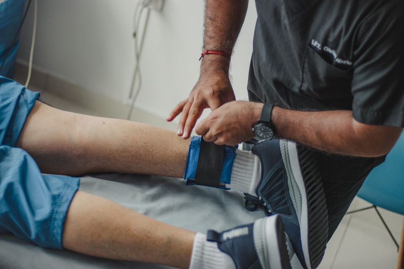 Clinician assessing a patient's knee and leg during a pain management consultation in a clinic