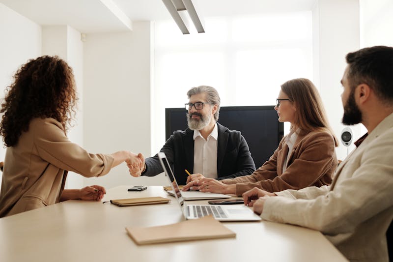 Business meeting with two people shaking hands across a table