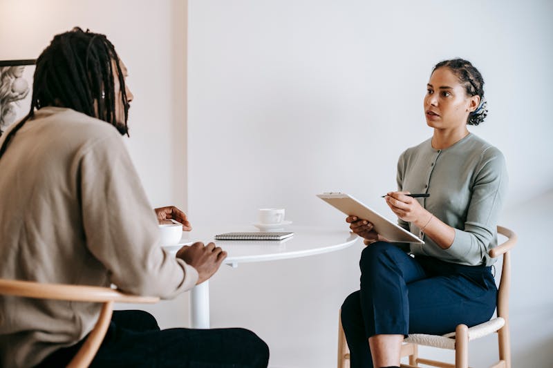 Two people talking across a small table during a consultation