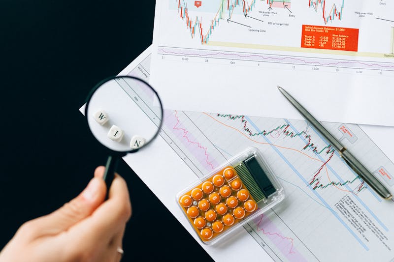 Magnifying glass held over printed trend charts on a desk