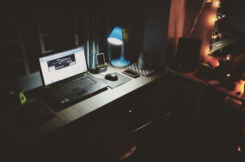 Laptop open on a desk under a lamp in a dim office