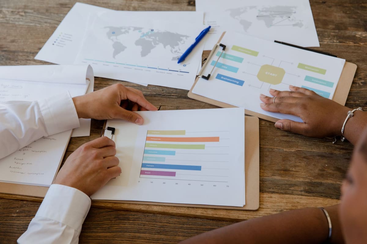 Colleagues at a wooden table reviewing printed bar charts